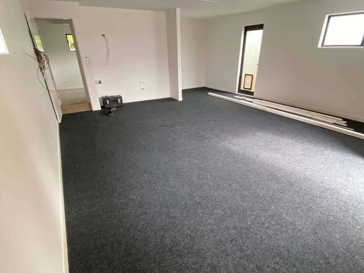 Carpet installer securing grey carpet neatly along a wall edge