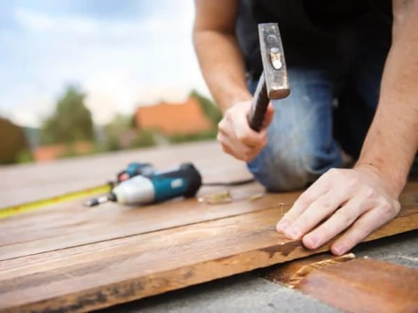 Flooring installer fastening a natural timber floorboard during installation